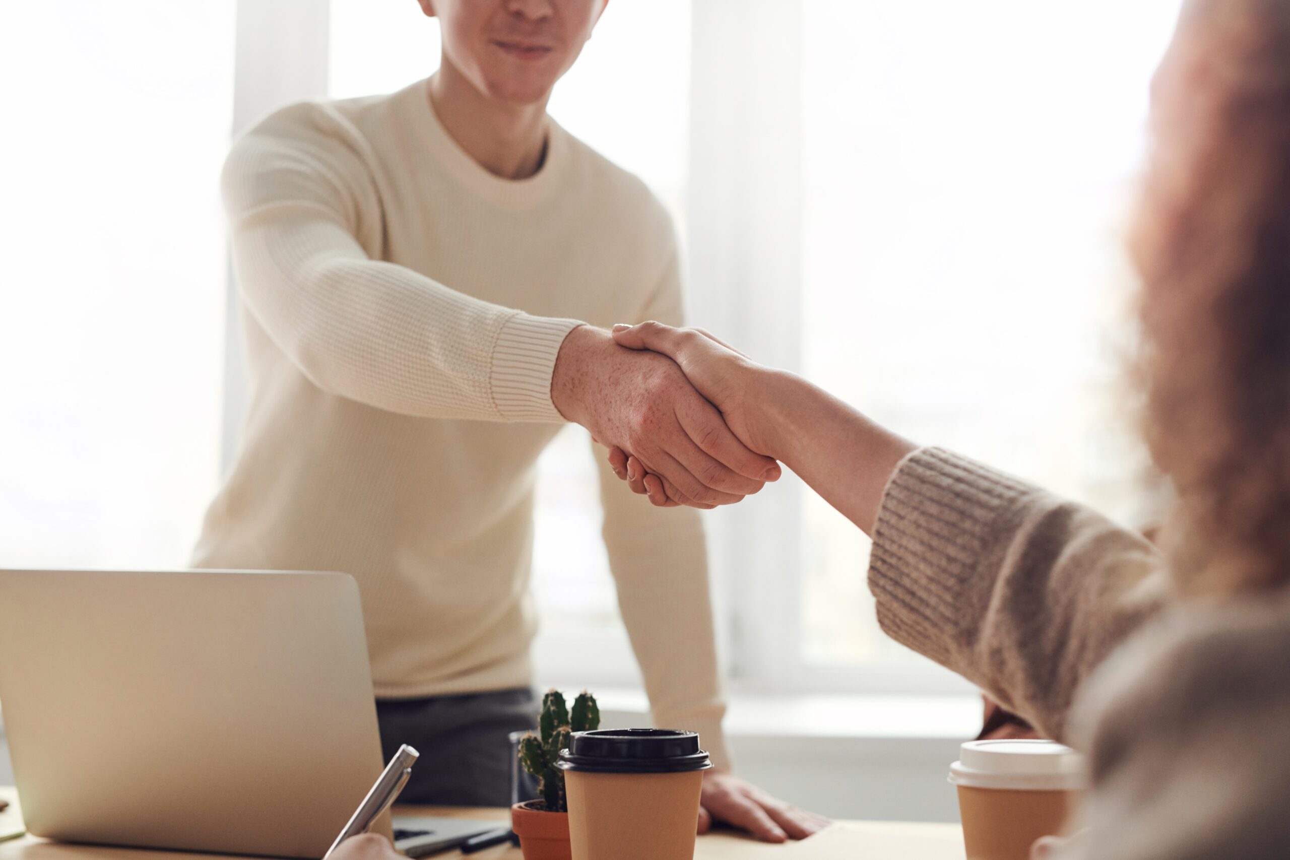 Business owner shaking hands over a desk with a new client.
